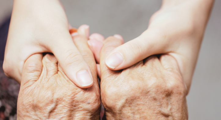 due mani anziane, sostenute e tenute delicatamente da mani più giovani